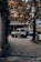A rugged SUV is parked on a cobblestone driveway in front of a hotel with a classic European facade. Lush greenery, including trees with dense leaves, frames the scene, and soft, diffused lighting suggests an overcast day.