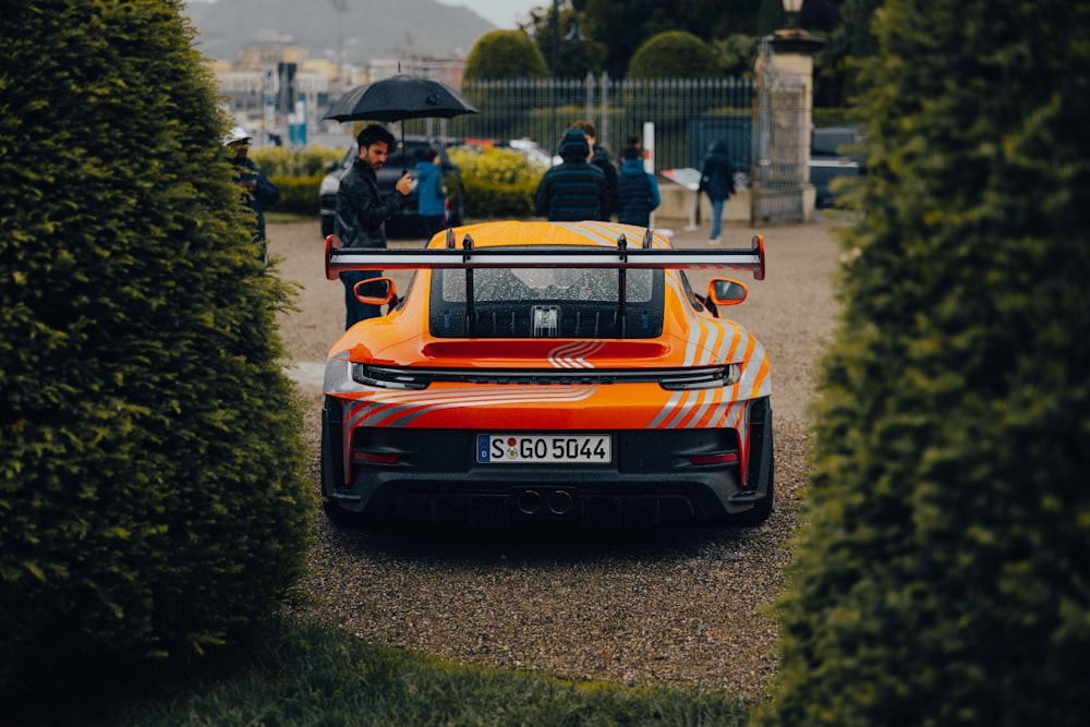 an orange sports car parked in a driveway