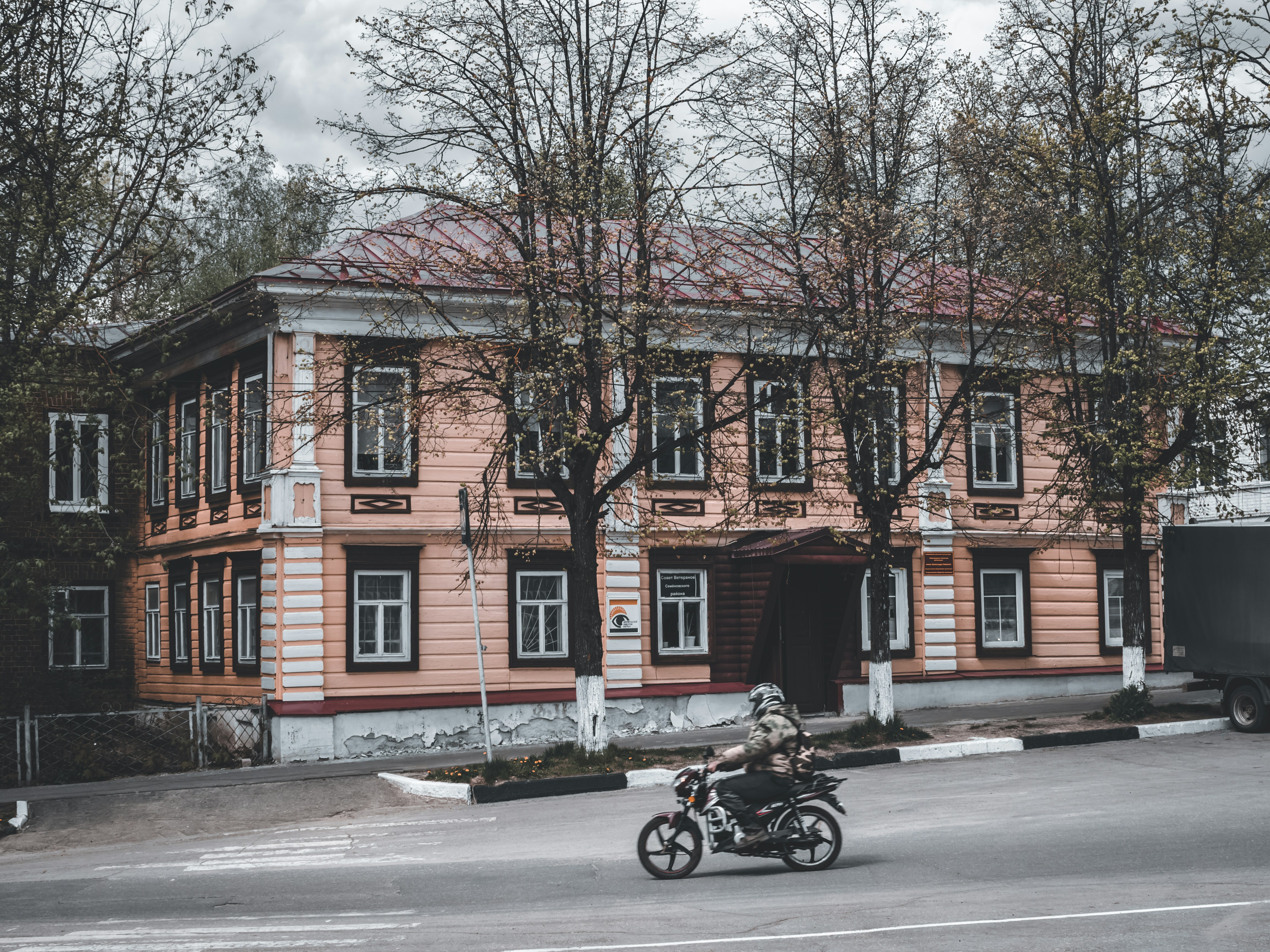 a person riding a motorcycle in front of a pink building