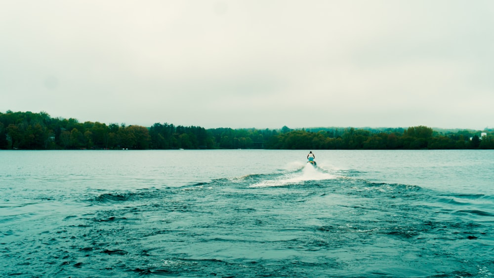 a person water skiing on a lake with trees in the background