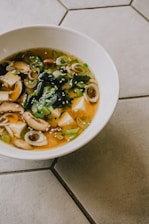 A steaming bowl of miso soup with fresh green onions and tofu cubes.