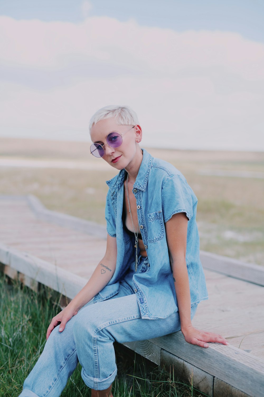 Une femme assise sur un banc en bois portant des lunettes de soleil