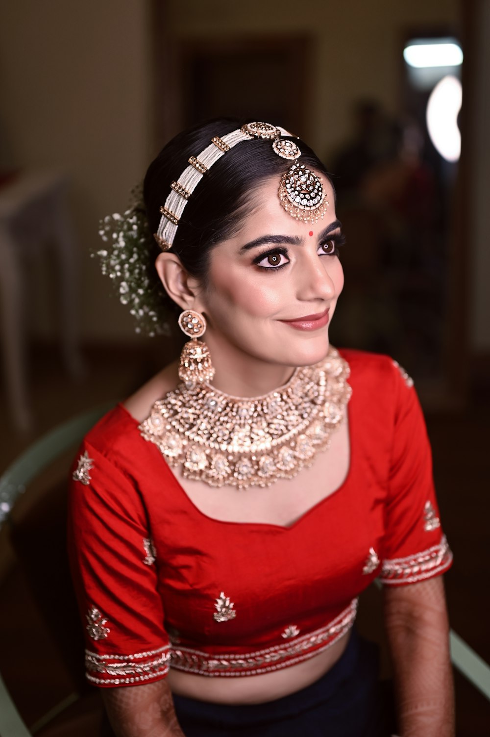 a woman wearing a red blouse and gold jewelry