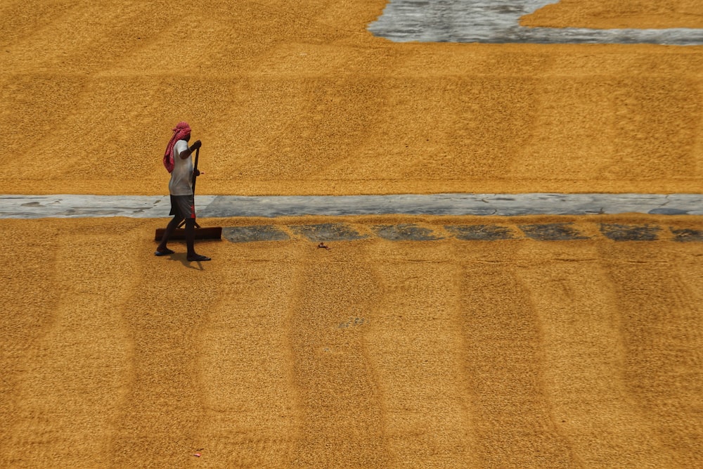 Una persona che cammina in un campo con un cappello rosso