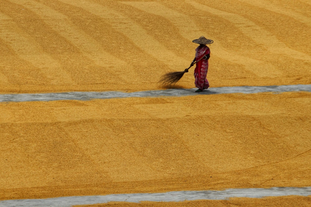 a person with a hat and a broom in a field