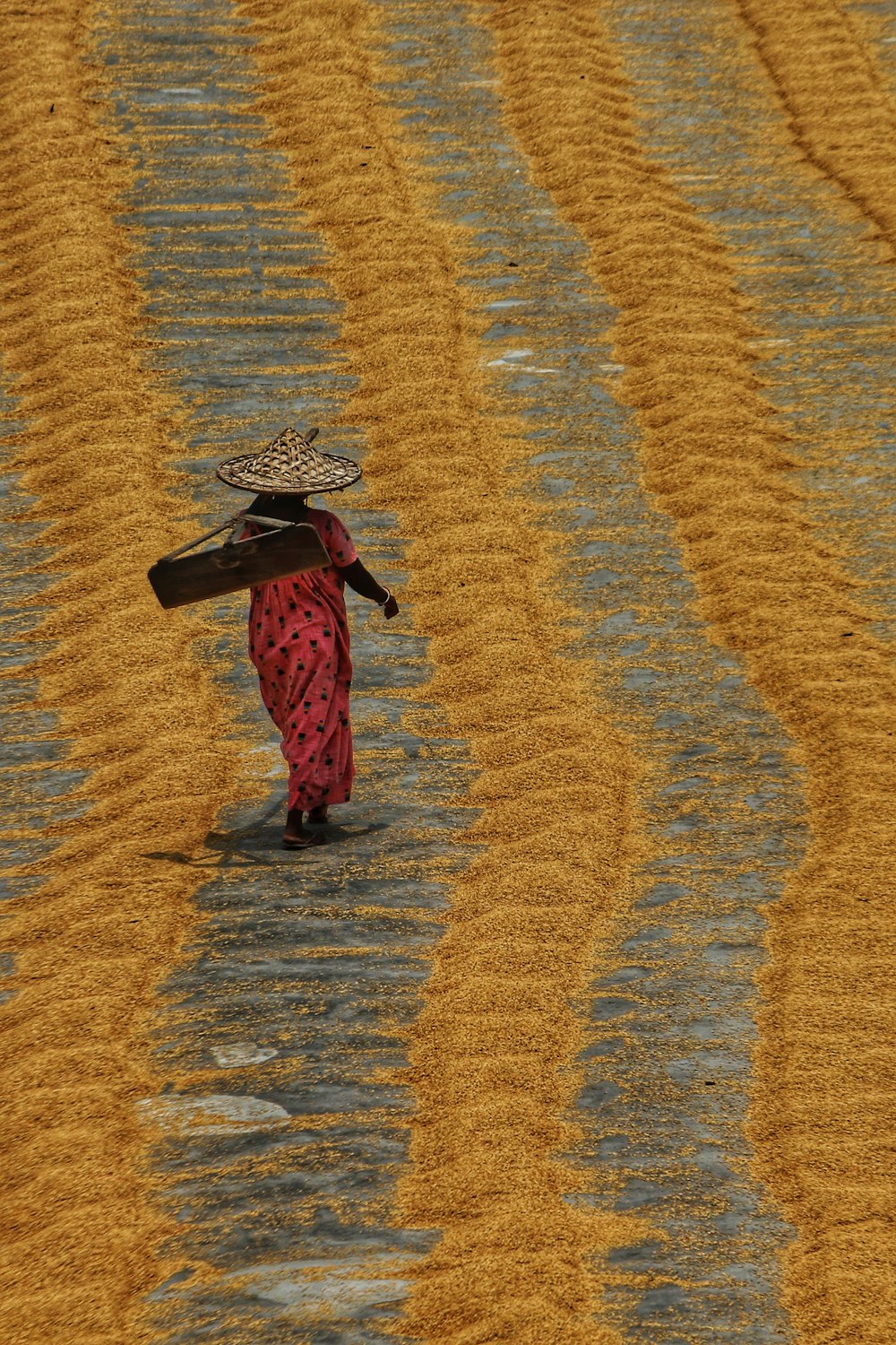 a woman walking across a field with a hat on her head