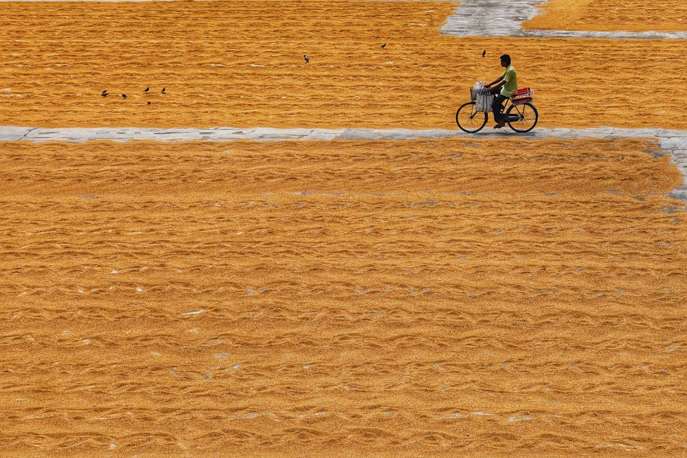 um homem andando de bicicleta por um campo de grama seca