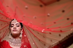 a woman in a red outfit with a veil over her head
