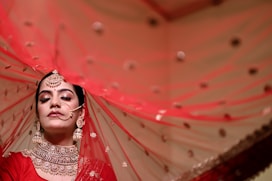 a woman in a red outfit with a veil over her head