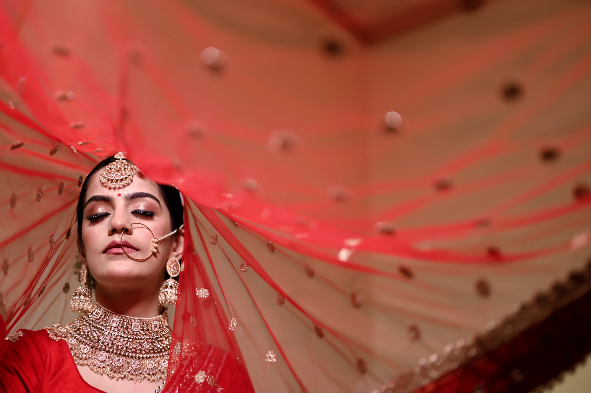 a woman in a red outfit with a veil over her head