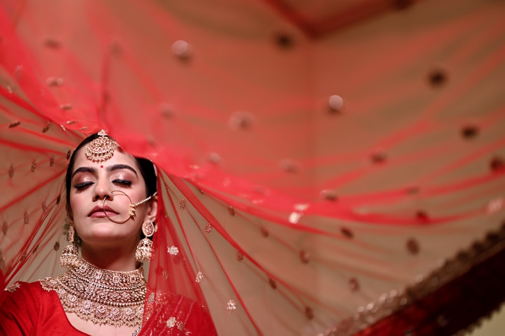 a woman in a red outfit with a veil over her head