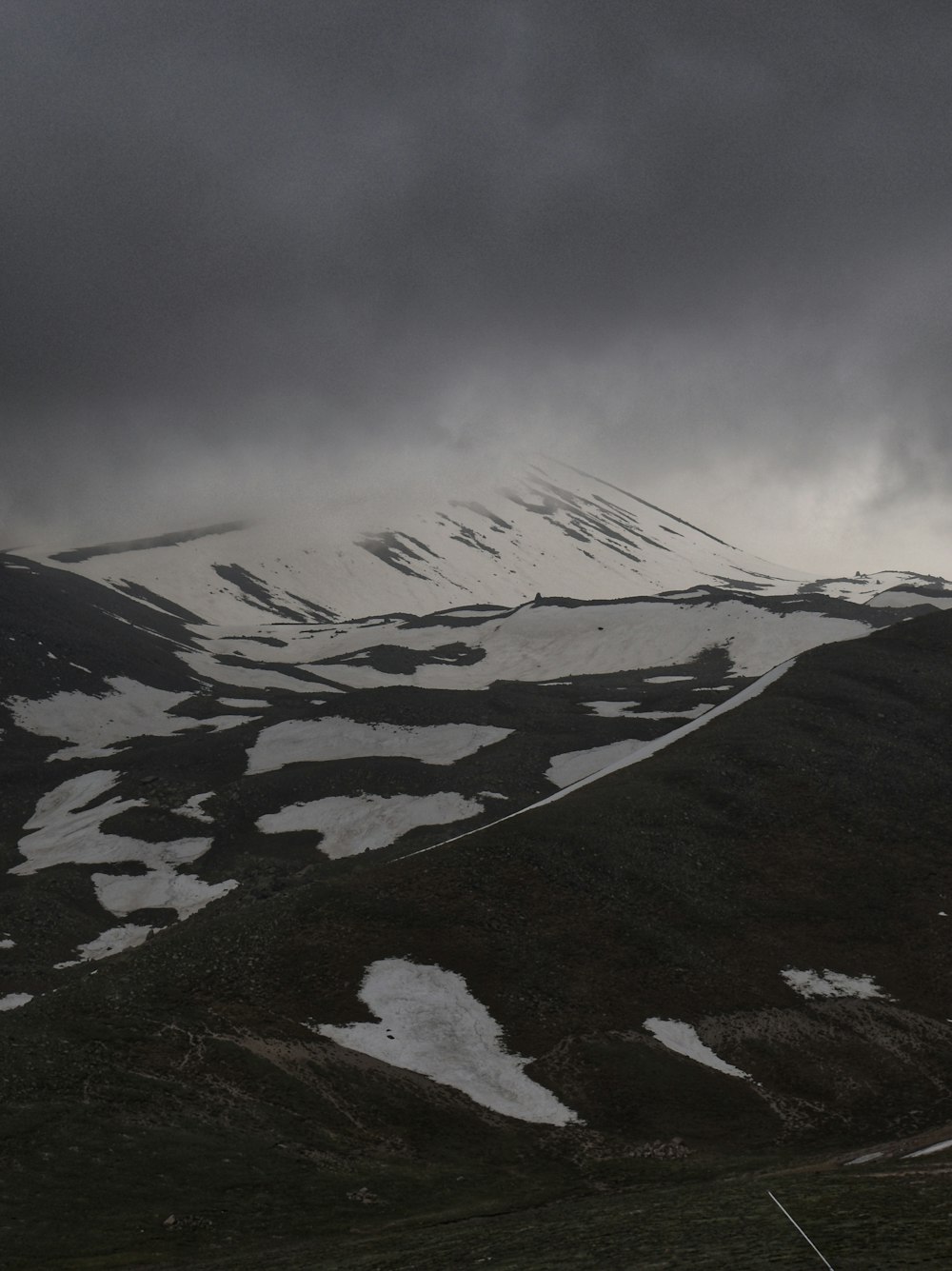 a mountain covered in snow under a cloudy sky