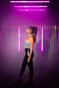A sleek model wearing a deep matte black oversized t-shirt with electric purple accents, standing against a neon-lit urban backdrop.