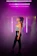 A radiant model wearing a glowing black and neon rave outfit against a dark urban backdrop.
