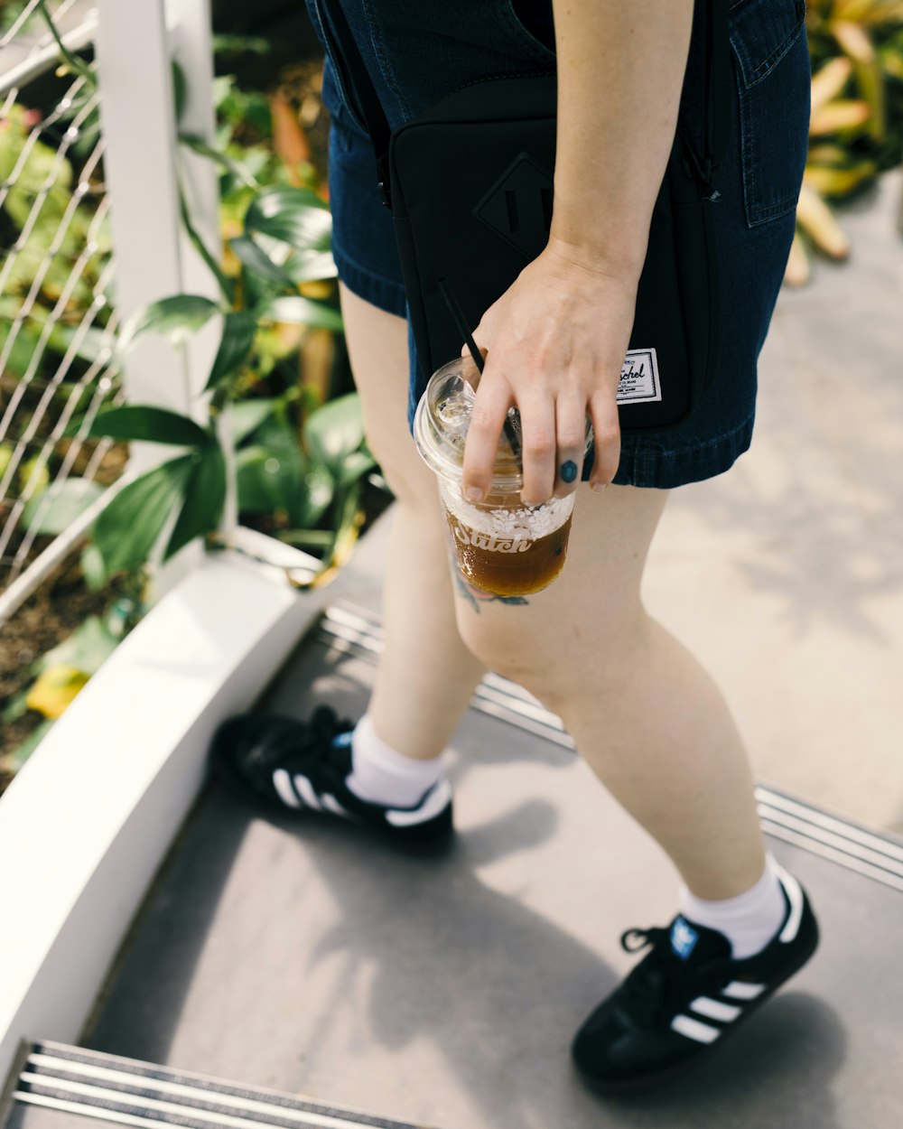 a person wearing black shoes and holding a drink