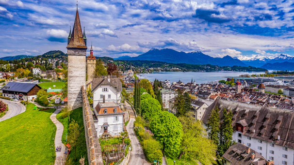 an aerial view of a city with a lake and mountains in the background