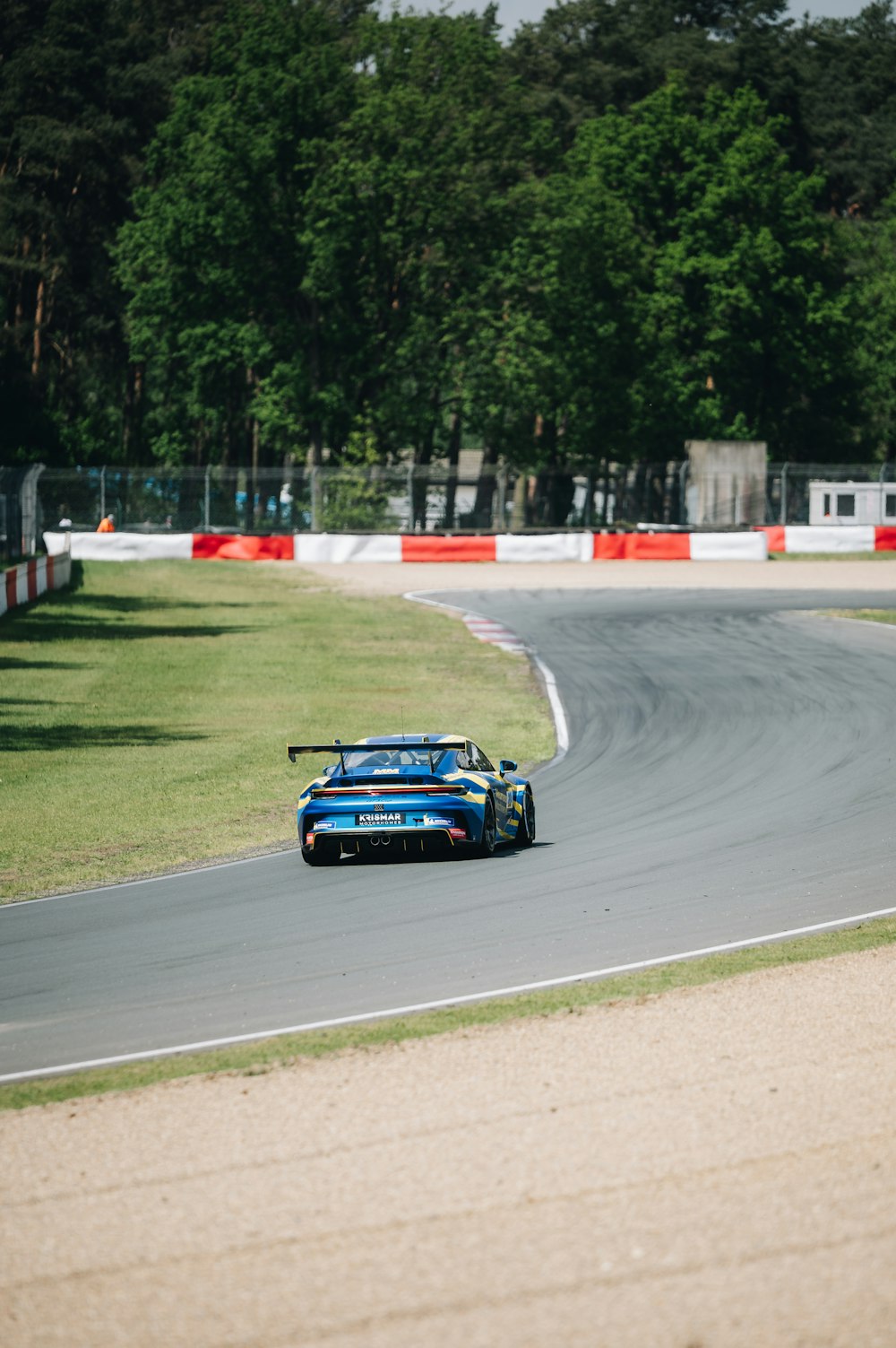 a blue race car driving down a race track