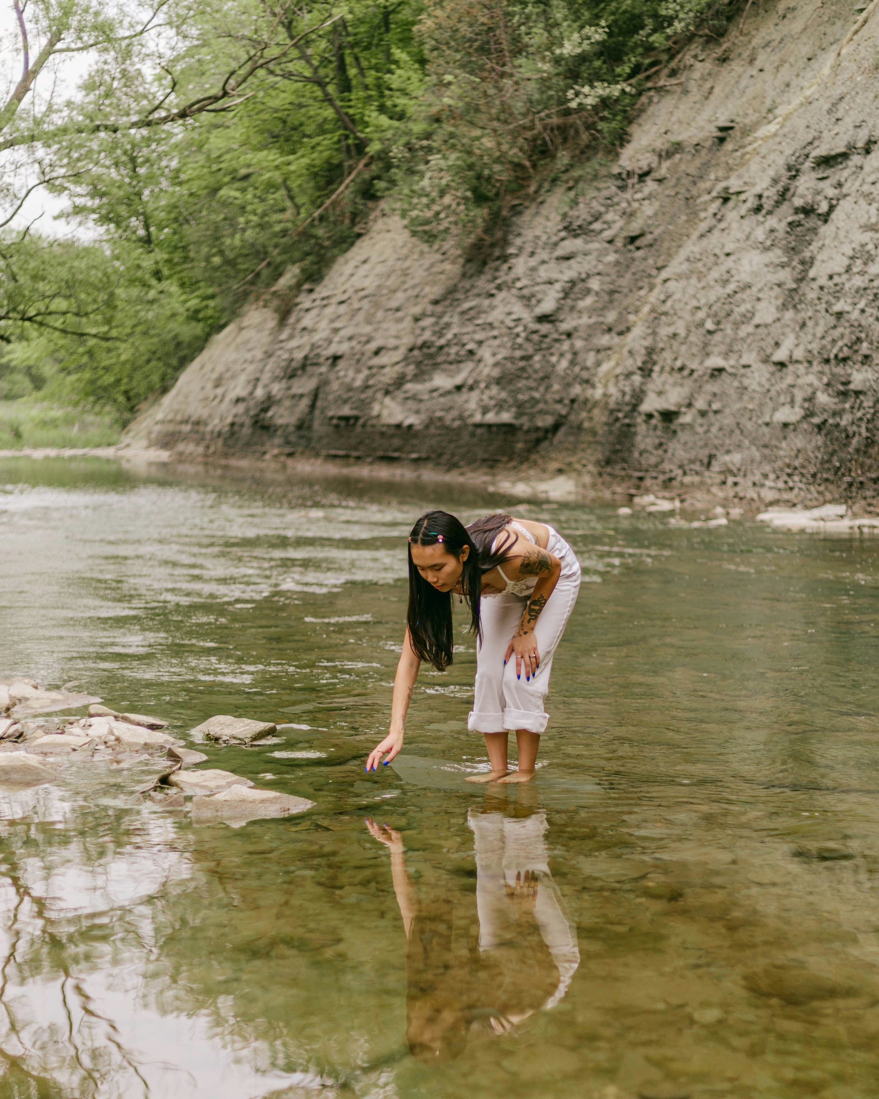 eine frau, die auf einem felsen in einem fluss steht