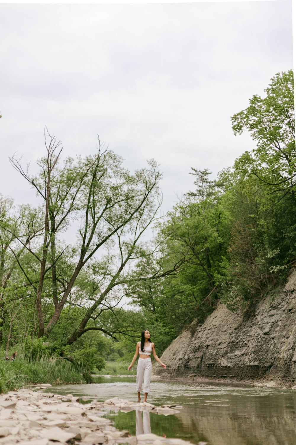 a woman standing on a rock in the middle of a river