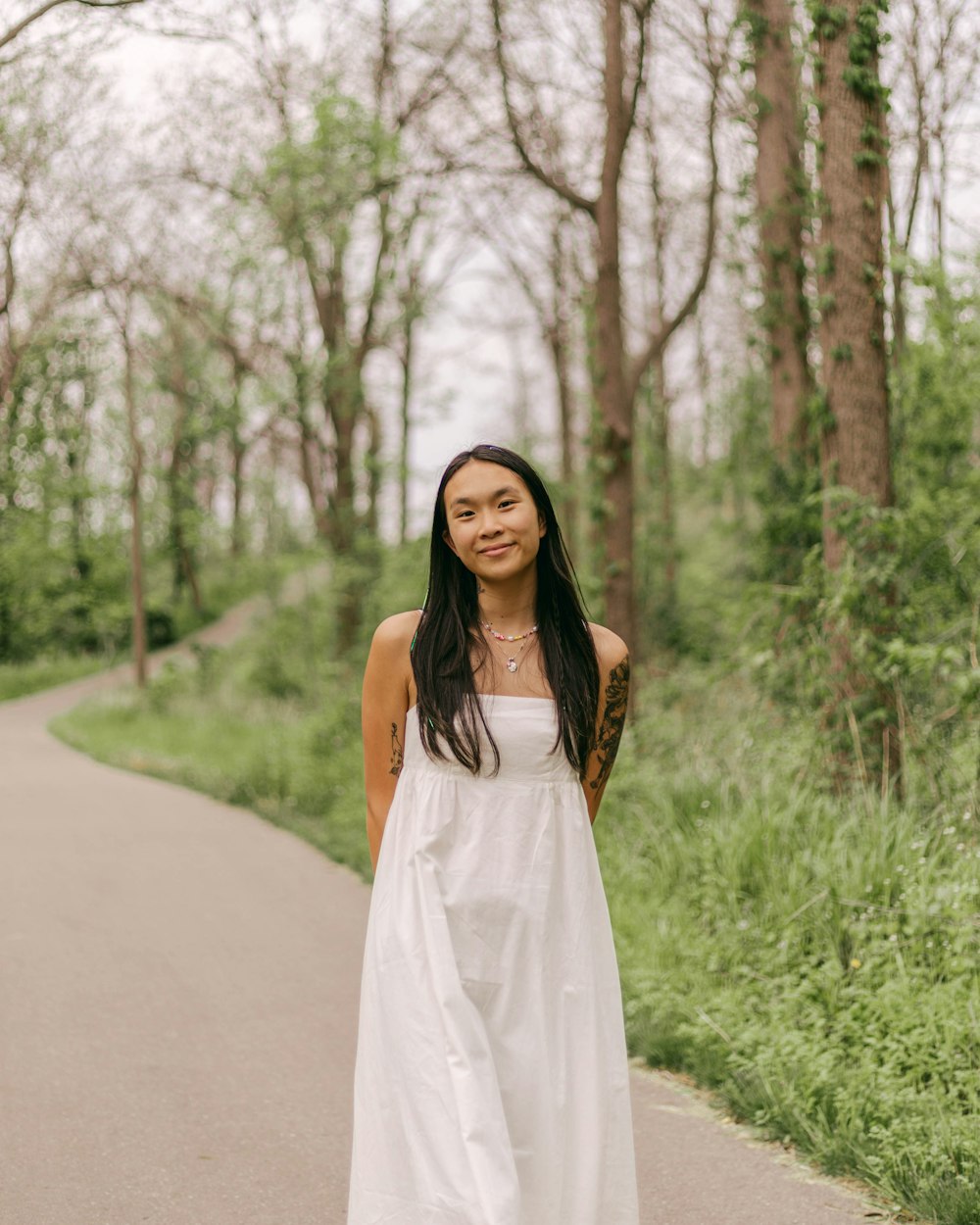 a woman in a white dress standing on a path