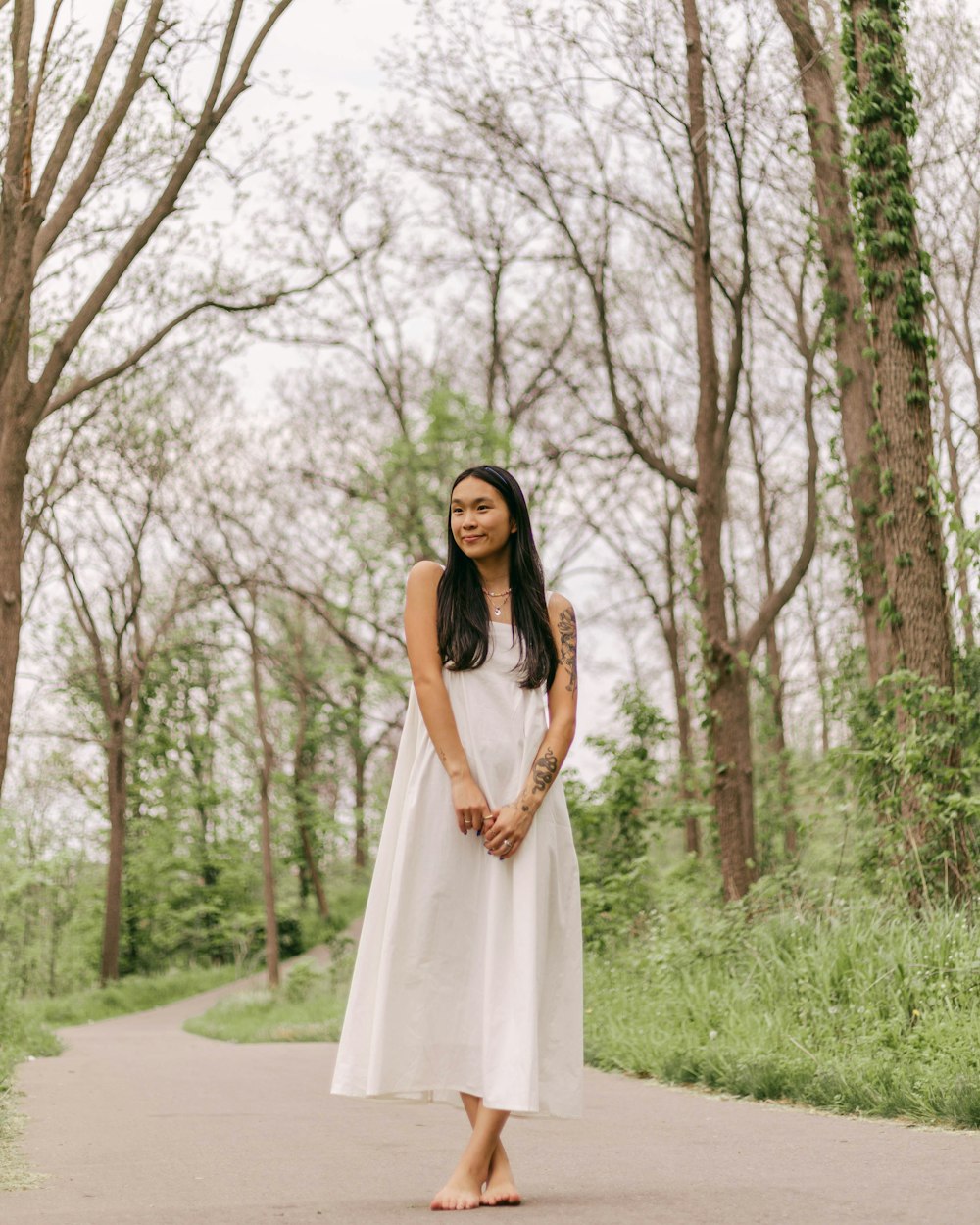 a woman in a white dress standing on a path