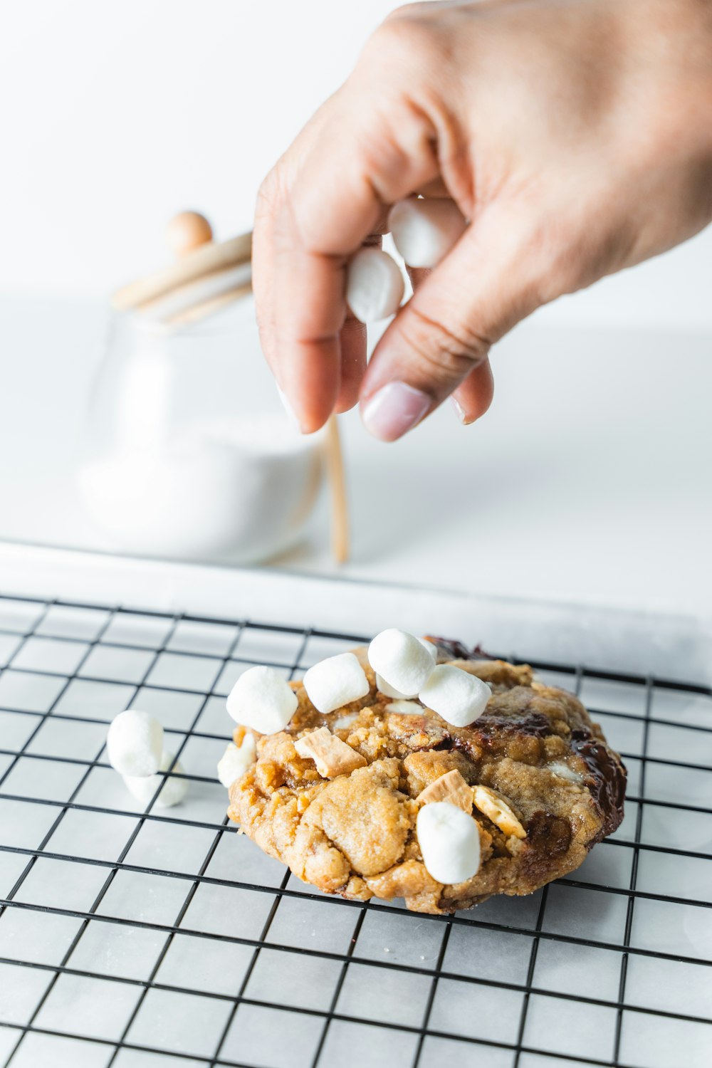 a person picking up a cookie with marshmallows