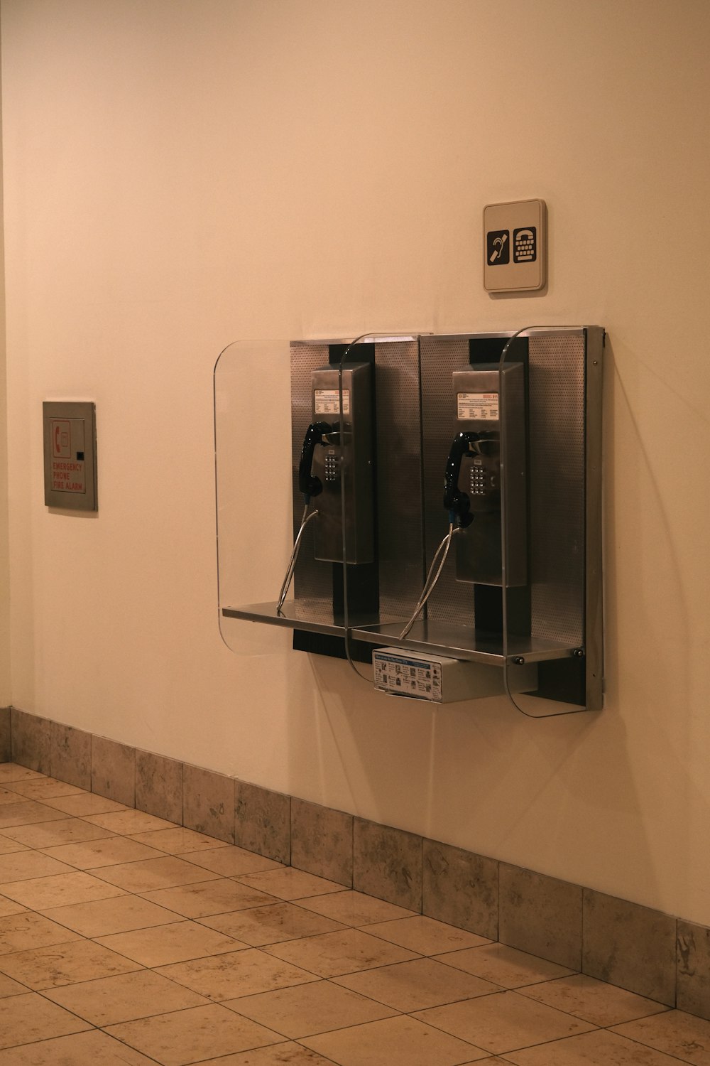 a wall mounted public phone next to a tiled floor