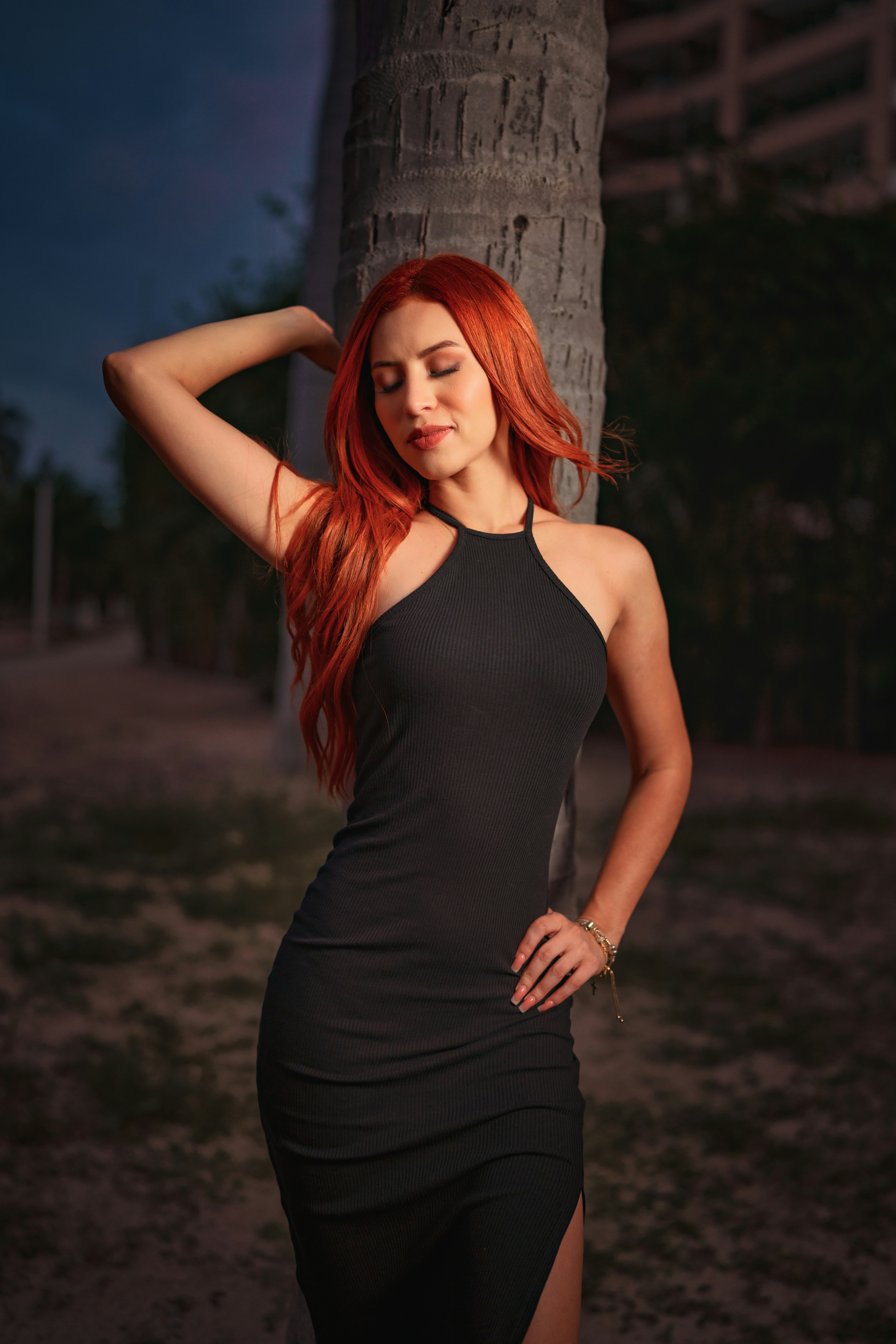 A beautiful portrait of a redhead model at the beach wearing a black dress taken at sunset