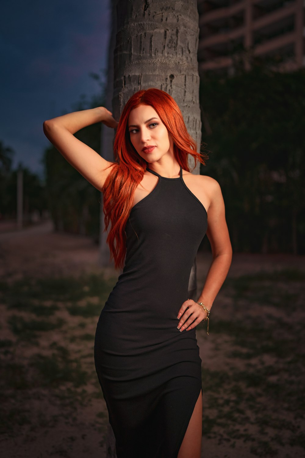 uma mulher em um vestido preto ao lado de uma árvore