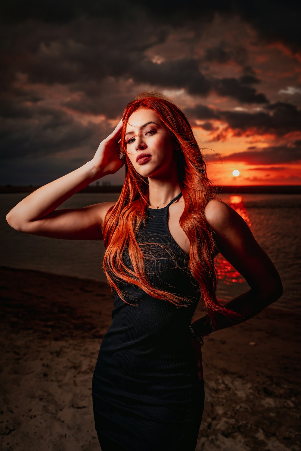 a woman with long red hair standing on a beach