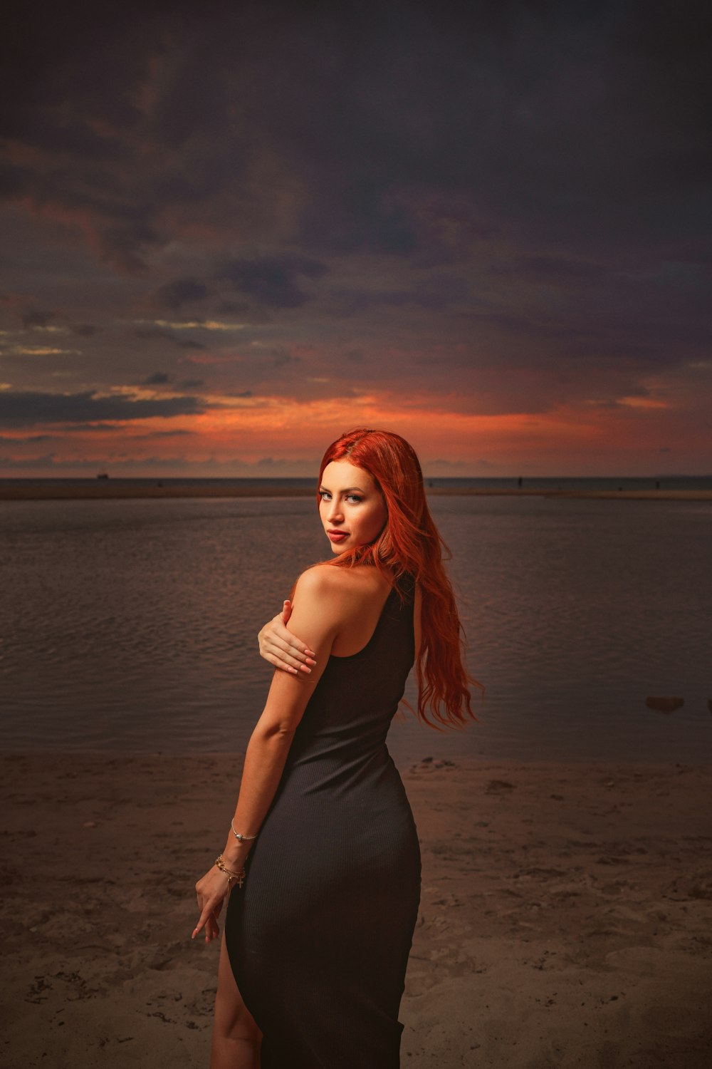 a woman with red hair standing on a beach