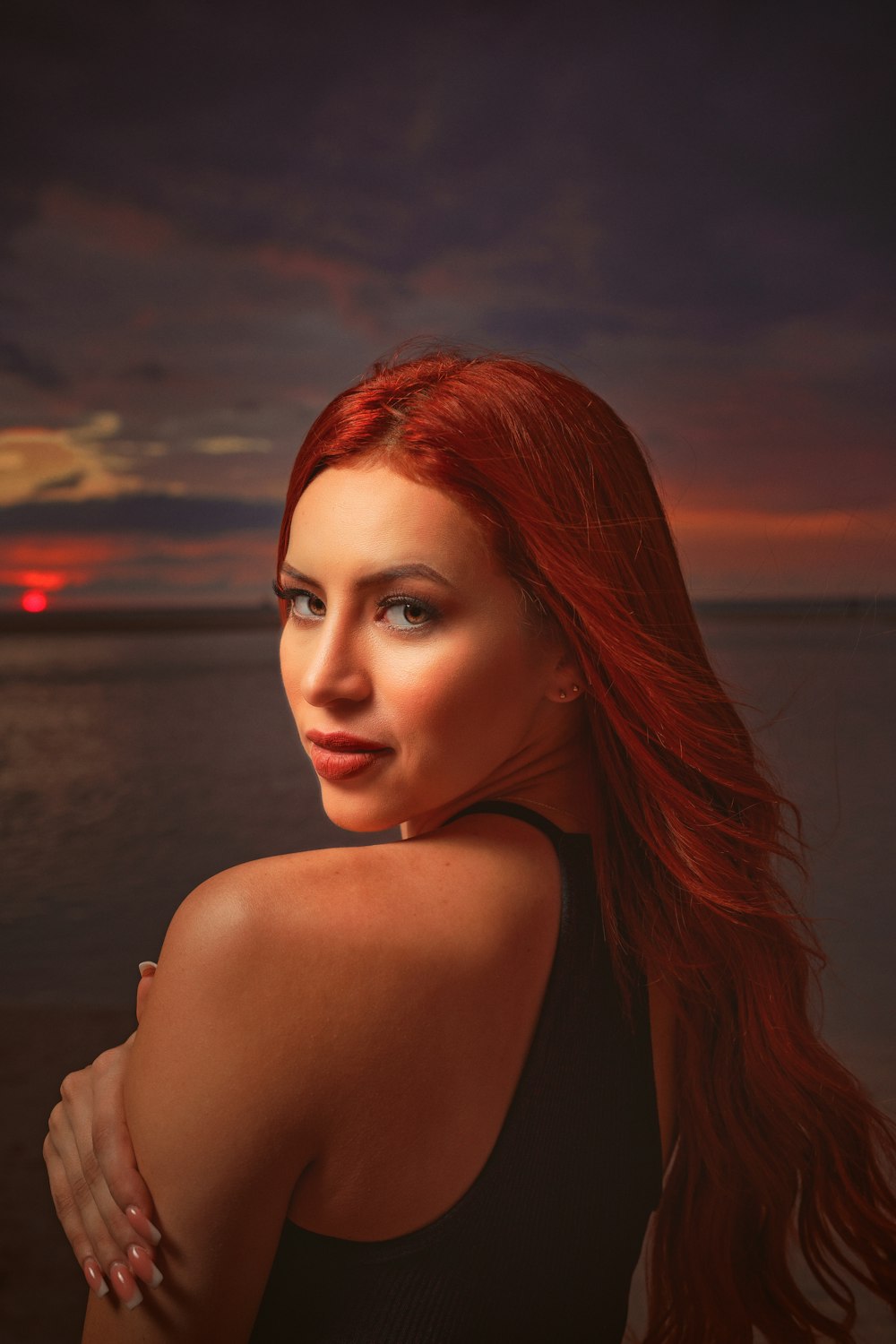 a woman with red hair standing on a beach