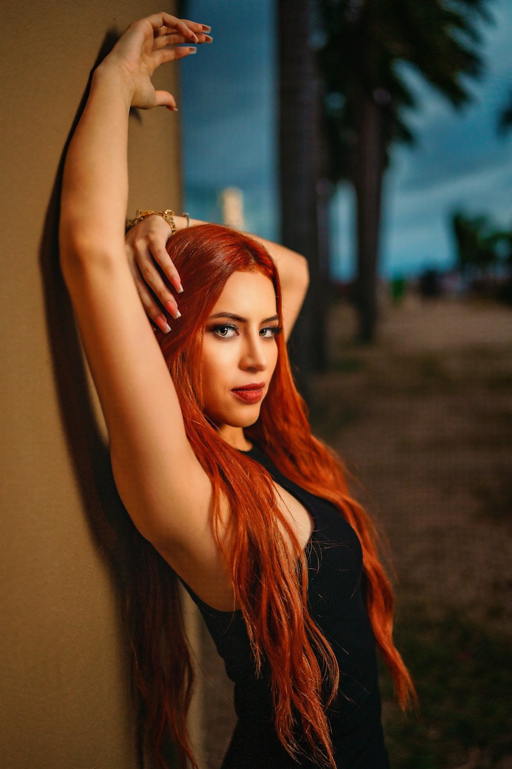 a woman with red hair leaning against a wall