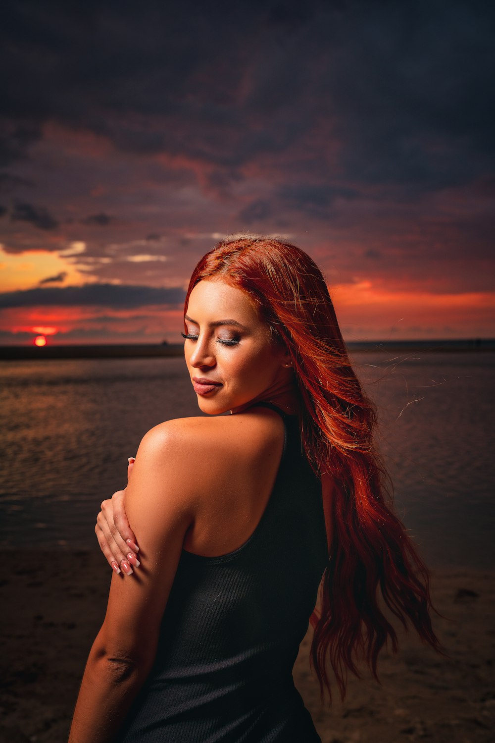 a woman with red hair standing on a beach