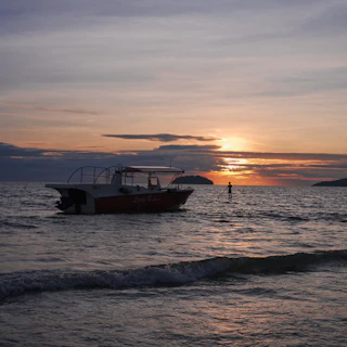 The diving center boat anchored near a calm bay at sunset.