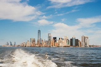 A panoramic view of New York City’s skyline at sunset as seen from a boat on the water.