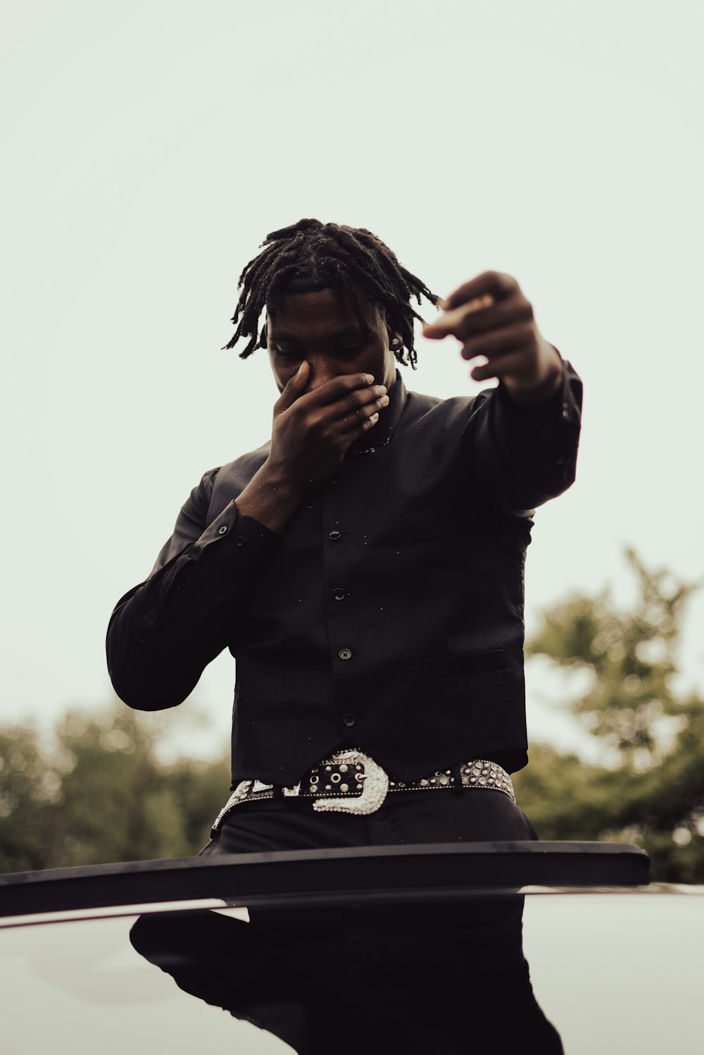 a man with dreadlocks standing in front of a car