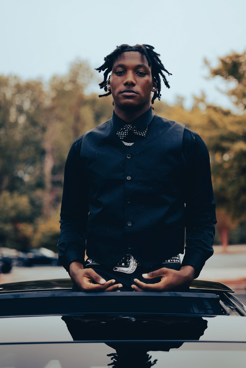 a man with dreadlocks standing on top of a car