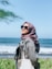 a woman wearing a headscarf and sunglasses looking at the ocean