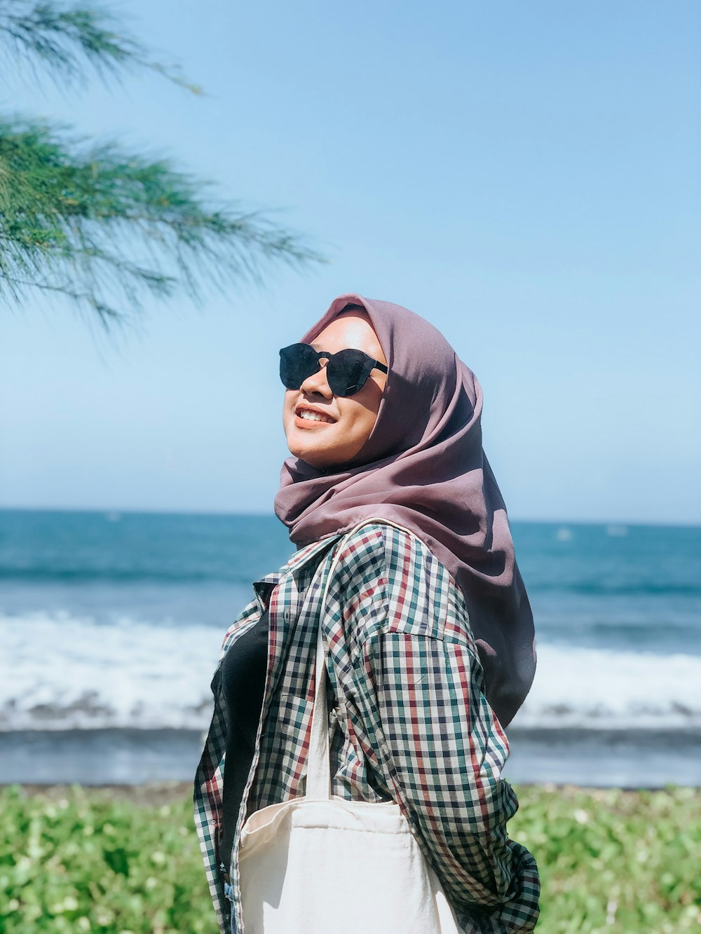 a woman wearing a headscarf and sunglasses looking at the ocean