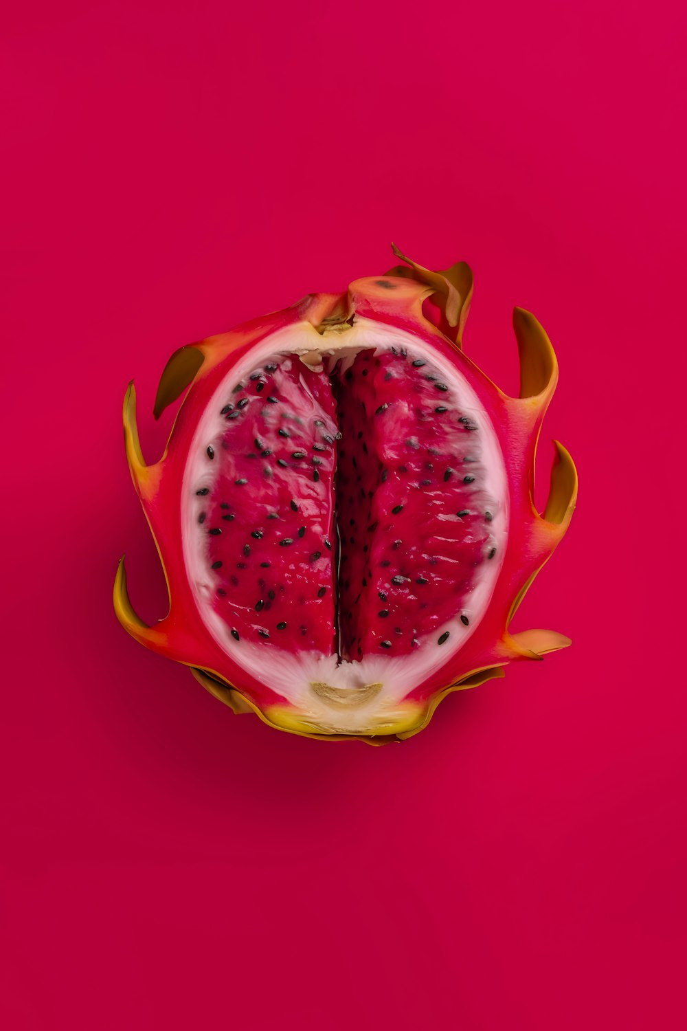 a dragon fruit cut in half on a pink background
