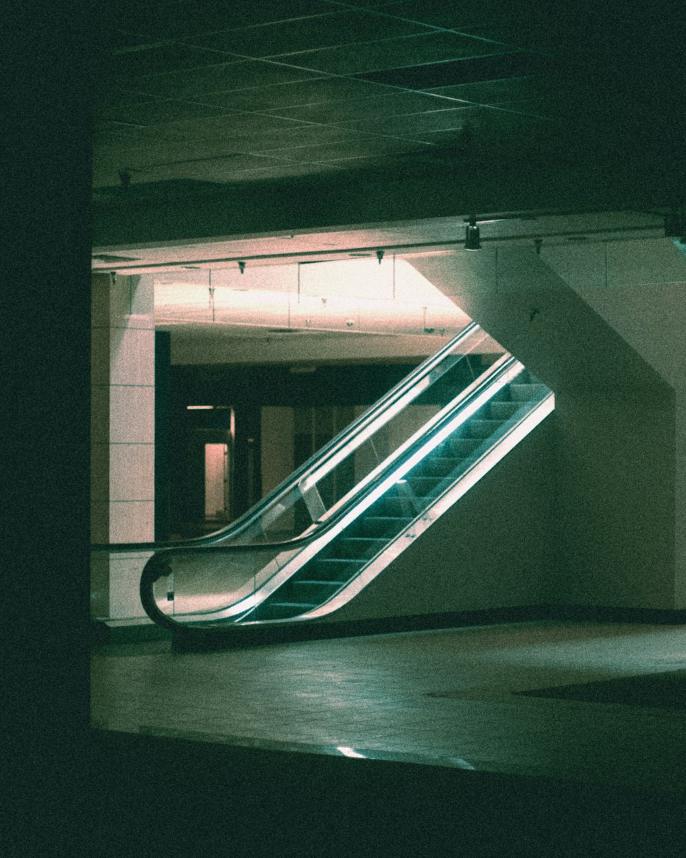 an escalator in a building with a light coming from it