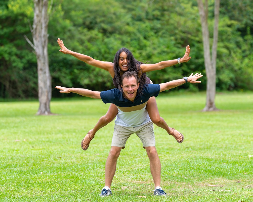 a man and a woman doing a handstand in a park