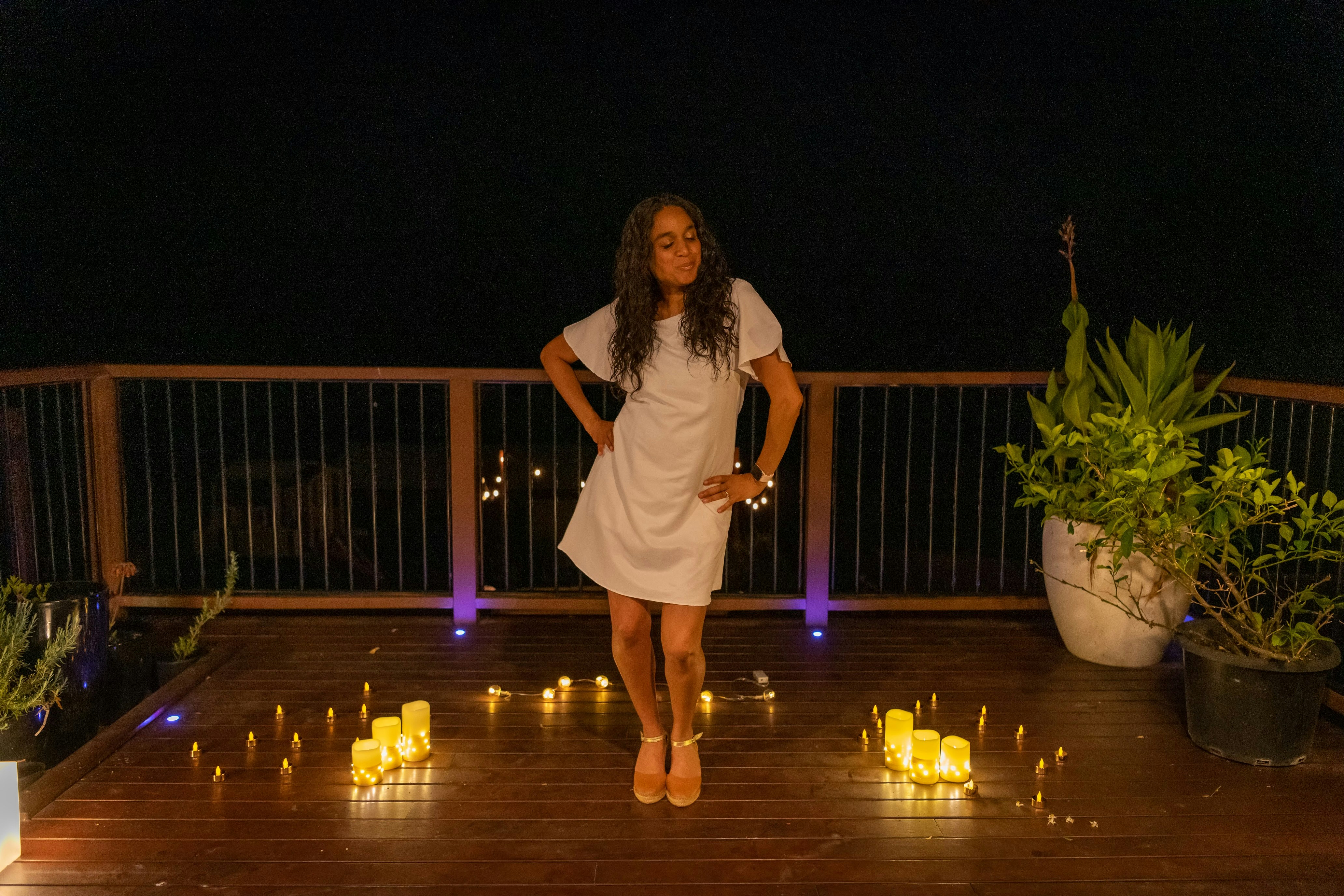 a woman standing on a deck surrounded by candles