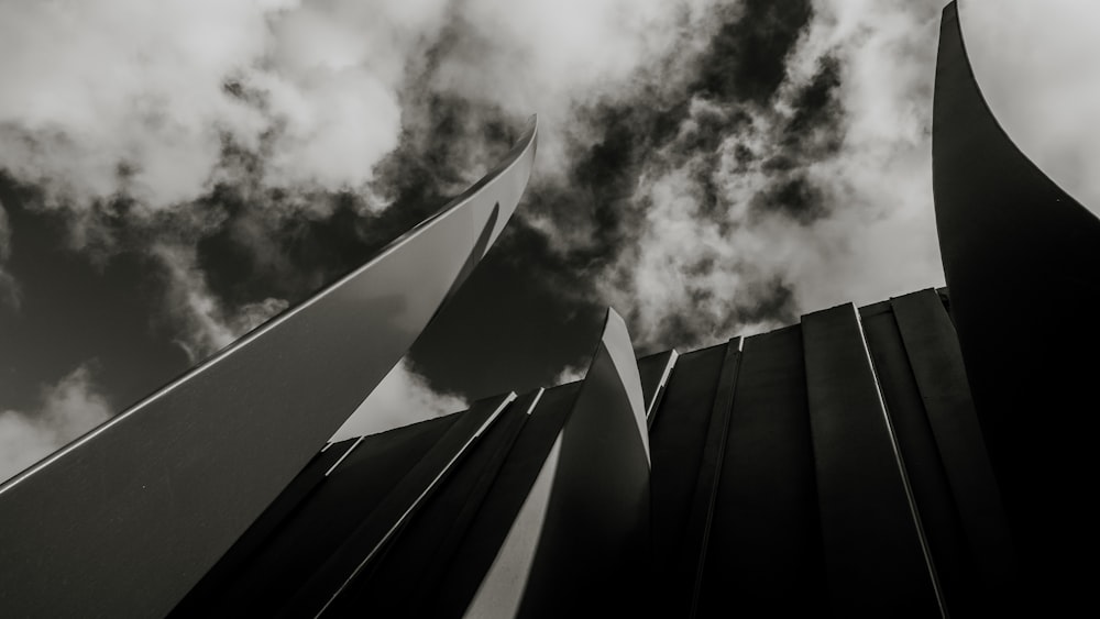 a black and white photo of a building with clouds in the background