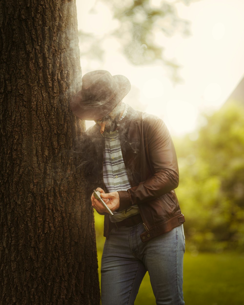 a person standing next to a tree using a cell phone