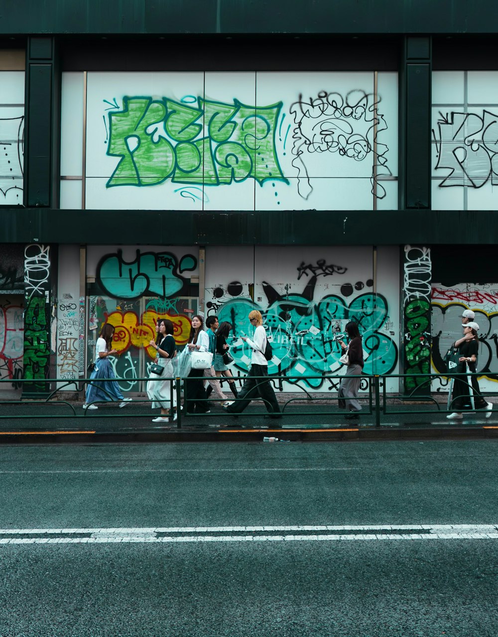 a group of people walking past a building covered in graffiti