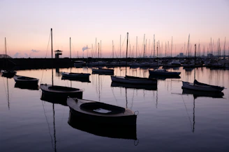 A calm Mediterranean harbor at sunset with an elegant anchor subtly integrated into the scene.