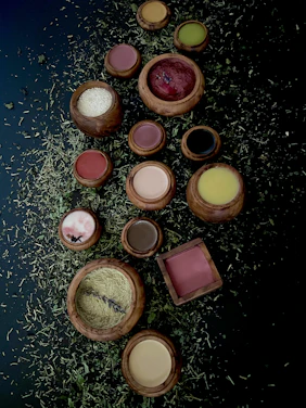 Close-up of vibrant henna and indigo powders in rustic bowls surrounded by fresh herbs.