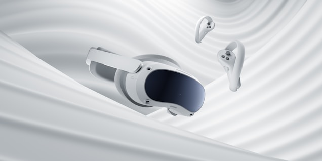 A virtual reality headset and two controllers are suspended against a backdrop of smooth, swirling white fabric, evoking a sense of fluidity and modern technology.